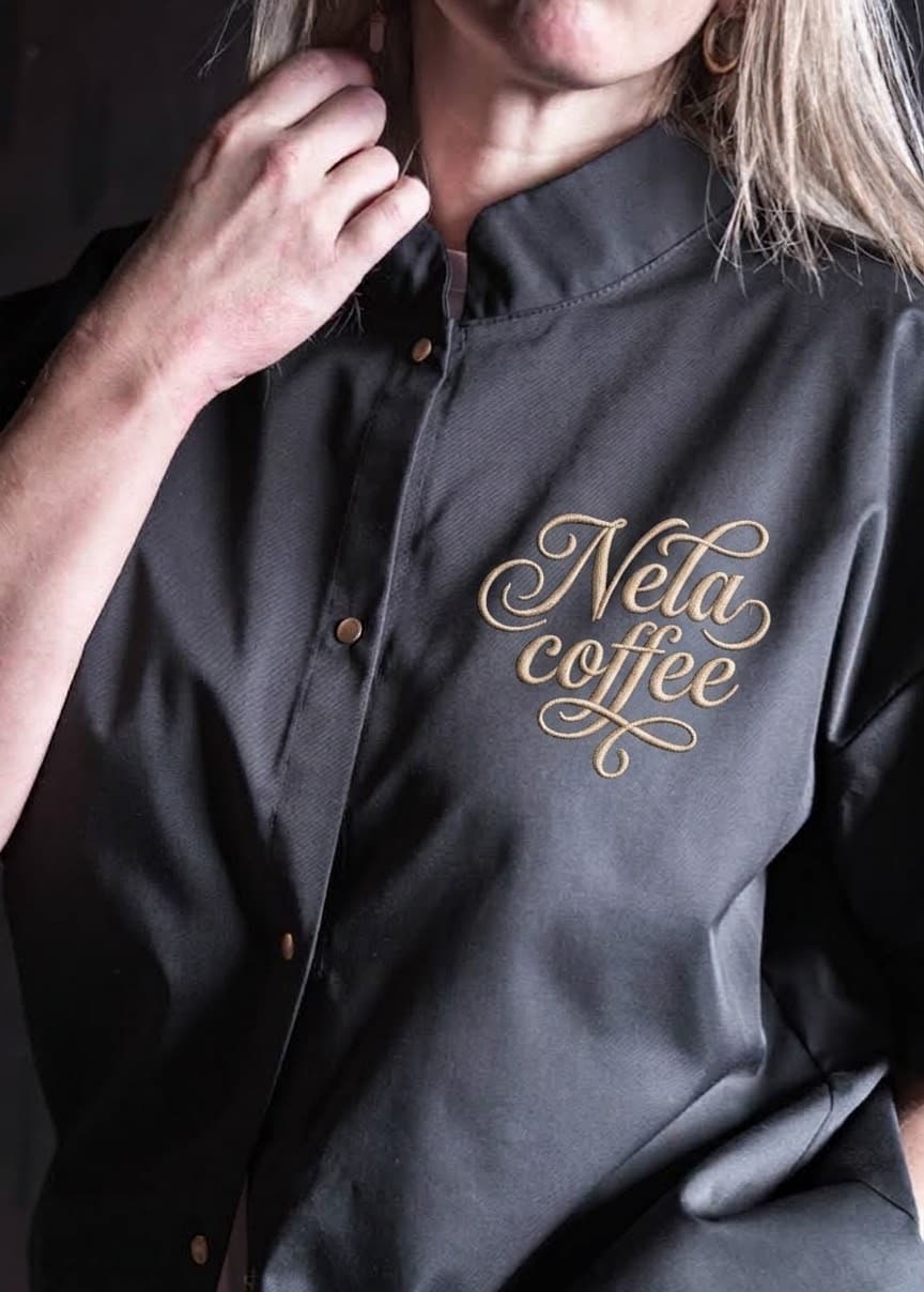 Gold Nela coffee logo embroidery on a slate chef top